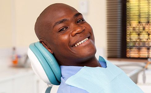 Smiling man in dental chair after emergency dentistry