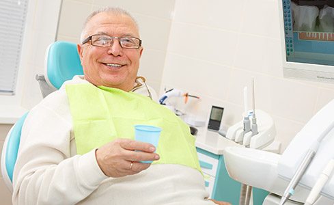 Smiling older man in dental chair after tooth extractions