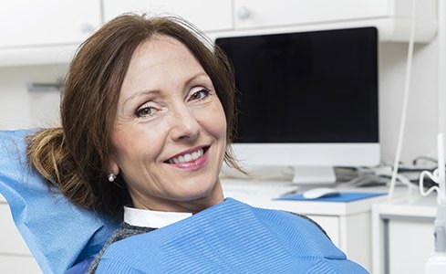 Older woman smiling in dental chair after laser periodontal therapy