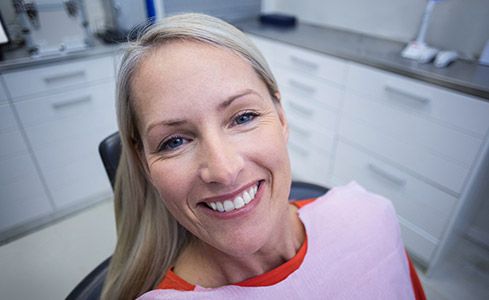Smiling older woman in dental chair after laser assisted periodontal therapy