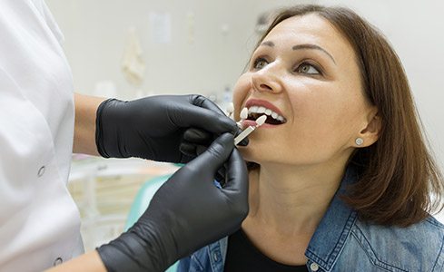 Dentist examining woman's teeth before porcelain veneer treatment