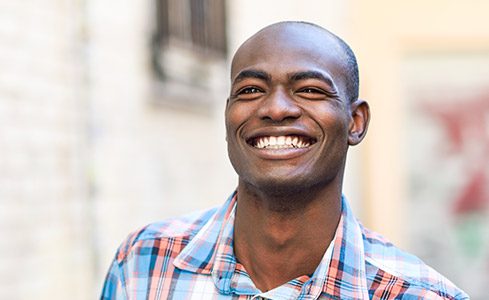 Young man with healthy flawless smile after dental crown and bridge restoration