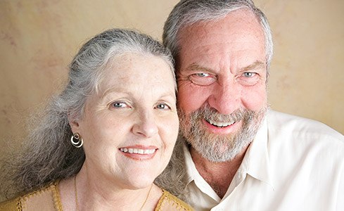 Older man and woman with dentures smiling together