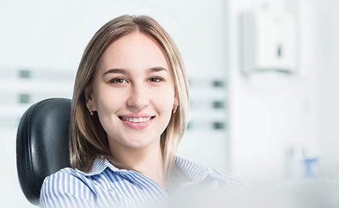 Smiling female dental patient in striped shirt