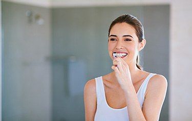 Woman in white shirt brushing her teeth