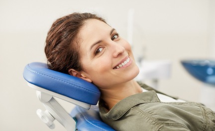 Woman sitting back in dental chair and smiling