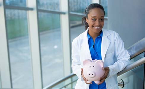 Smiling dentist holding a pink piggy bank