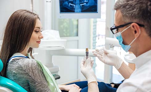 Dentist showing a dental implant to a patient