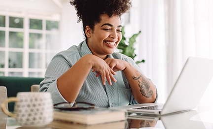 Woman smiling while working on laptop at home