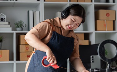 woman listening to music and taping a box closed