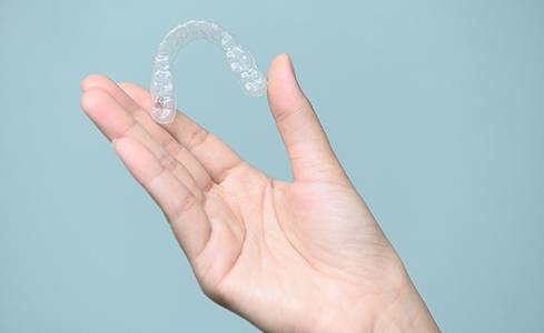 Patient holding up Invisalign clear aligner