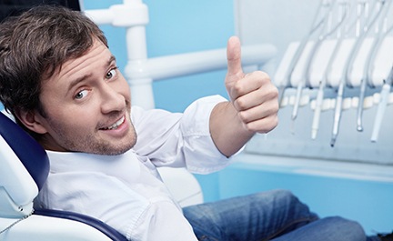 Male dental patient smiling and giving thumbs up