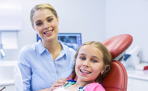 Dentist and young girl in dental exam room for pediatric dentistry appointment