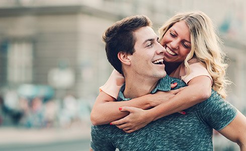 Smiling man and woman outdoors after preventive dental checkups and teeth cleanings