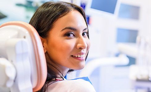 Woman in dental chair smiling after root canal therapy