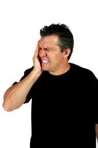 Man holding cheek in pain during dental emergency