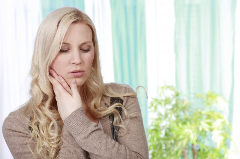 woman holding jaw in pain