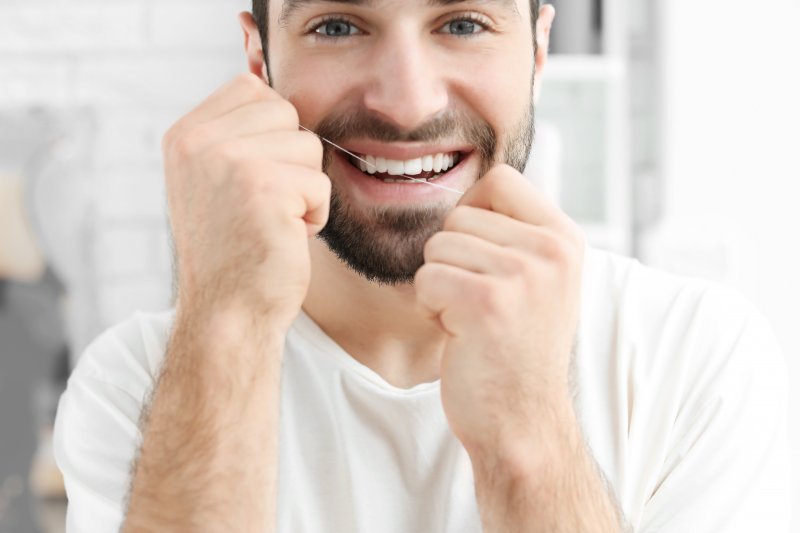 a young man flossing his teeth while waiting to see a dentist in Long Island City