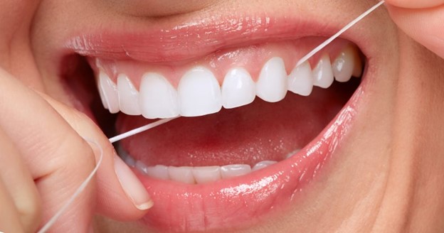 Closeup of a woman flossing her teeth.