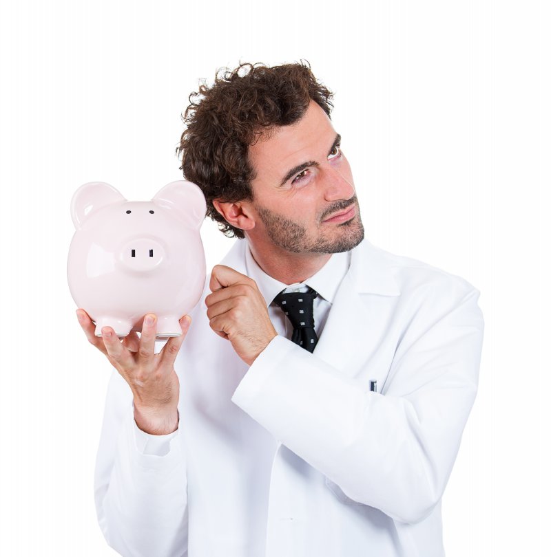 A dentist in Long Island City holding a piggy bank