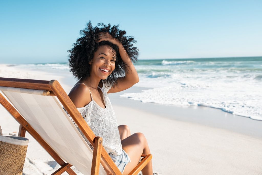 Woman smiling while relaxing on chair at the beach