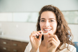 Woman sitting in dental chair covering her mouth